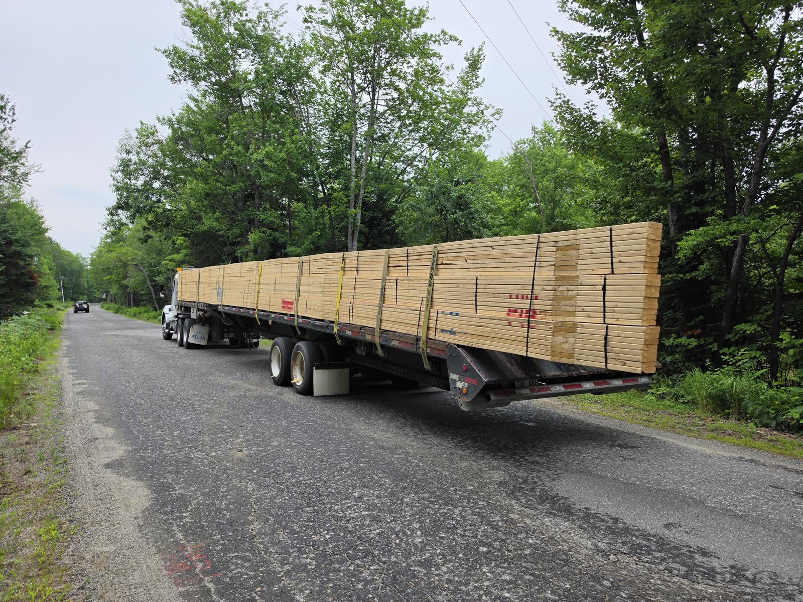 Roof trusses arriving on the flatbed at a Winter Construction garage build in Western Maine