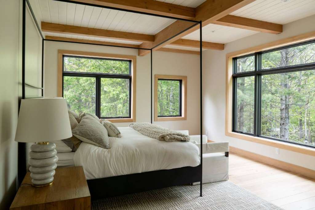 Primary bedroom canopy bed forest view winter construction phillips maine